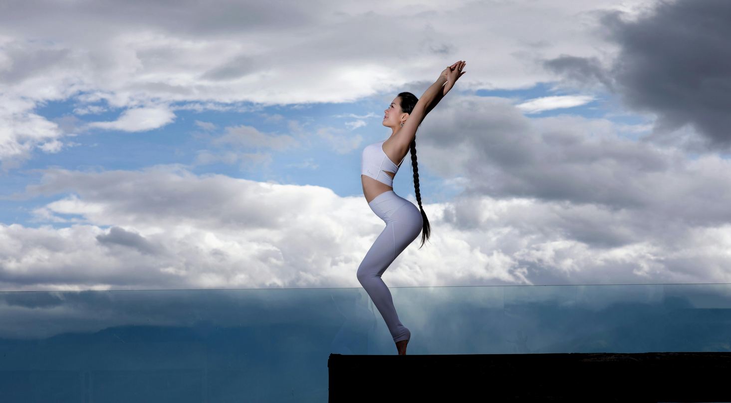 A woman in a yoga pose against a wide sky